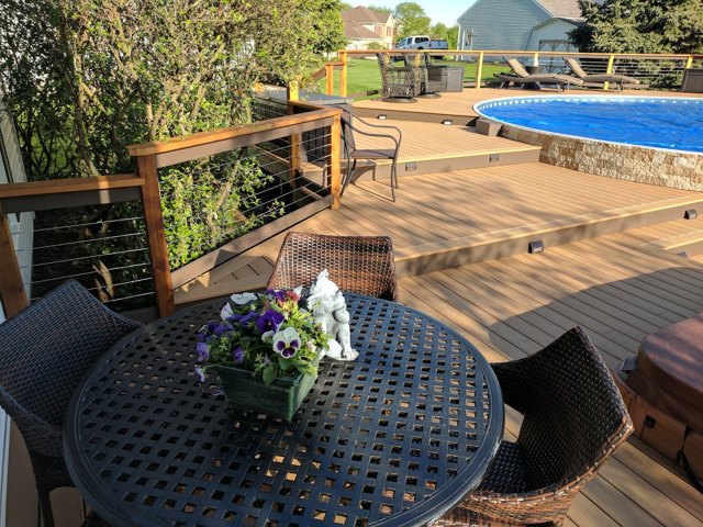 Decking, dining space, and wide steps around a stone-sided pool.