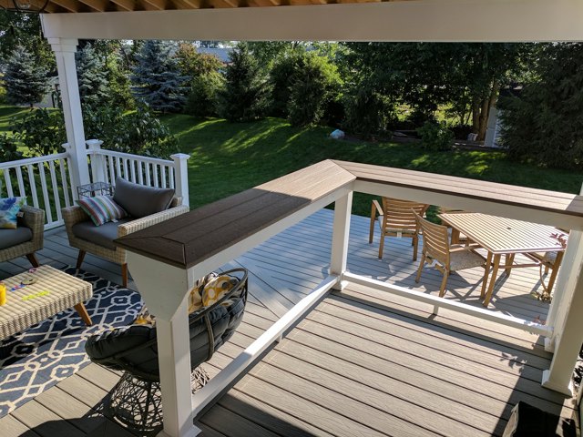 A covered seating area beside an open deck, with contrasting railing details.