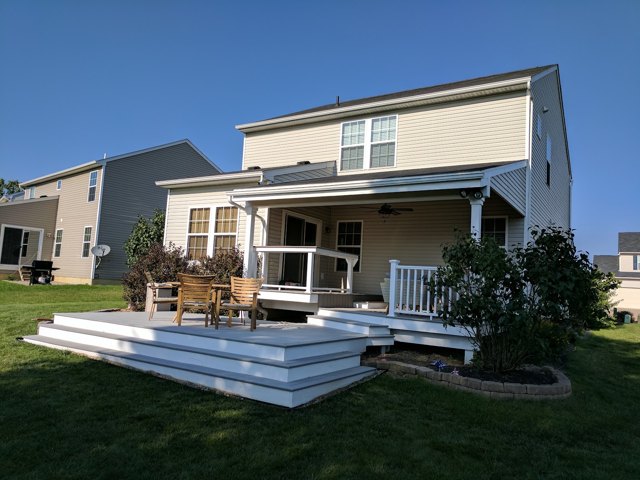 A covered porch and a low deck with broad steps and white trim.