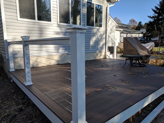 White posts and slender horizontal railing lines around a warm-toned deck.