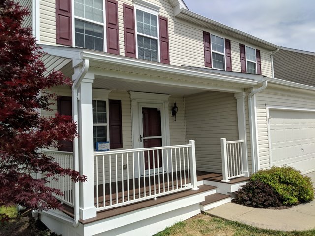 White posts and railings frame a porch beneath red shutters.