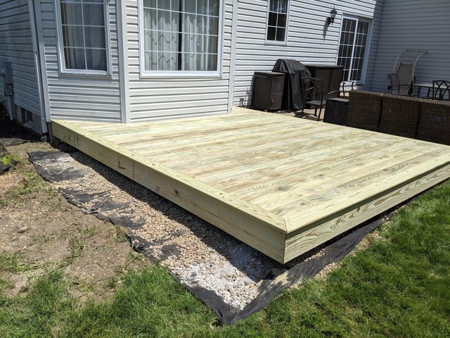 A low wood platform connects the back door with the lawn.