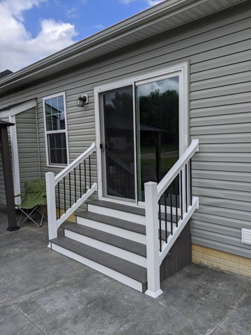 A compact gray landing with white posts, dark balusters, and matching steps.