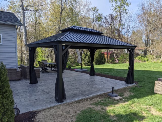 A dark pavilion creates a sheltered spot beside the house.