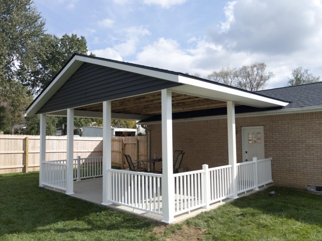 A roofed outdoor space with white railings and views toward the yard.