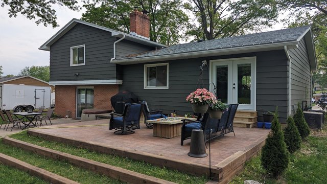 A wide, low wood deck with space for outdoor seating and access to the lawn.