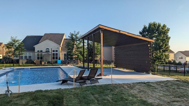 An open-sided structure offers shade at the edge of the swimming pool.