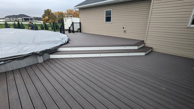 Gray decking and broad steps connect the pool edge with an upper gathering area.