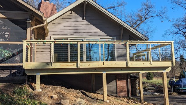 A raised wood deck with horizontal railing lines overlooking the yard.