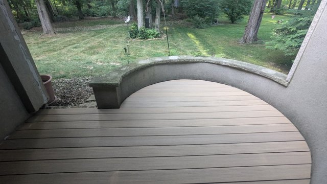 A rounded deck follows the garden wall beside a wooded outdoor space.