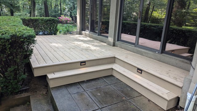 A compact deck and broad steps connect the doors to the patio, with inset stair lights.