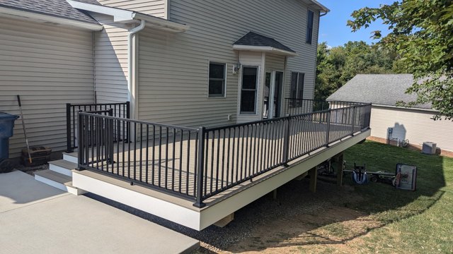 A backyard deck with black railings, pale trim, and steps to the yard.