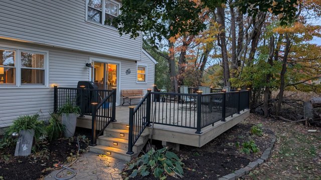 Warm stair lighting, black railings, and space to sit beneath the trees.