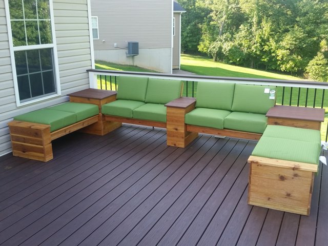 Warm-toned decking and dark balusters frame a colorful outdoor sitting area.