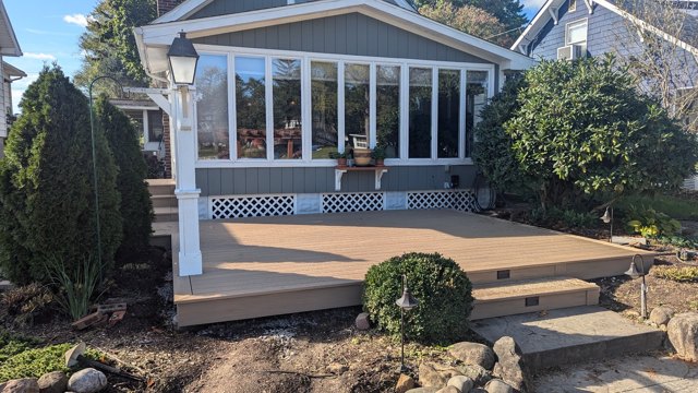 Warm decking and dark railings follow a curved edge beside the garden.